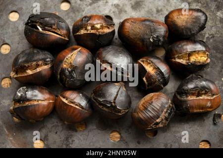 castagne arrosto nella tipica padella forata Foto Stock