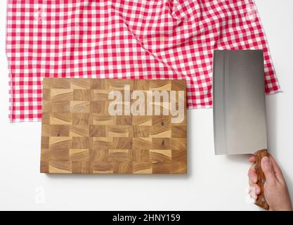 tagliere in legno vuoto e mano femmina che tiene un grande coltello da cucina affilato per tagliare la carne su sfondo bianco Foto Stock