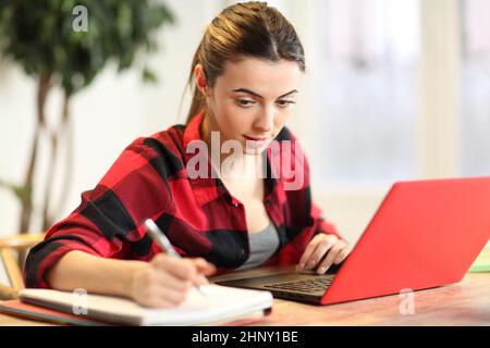E-learning concentrato degli studenti utilizzando il notebook e prendendo appunti a casa Foto Stock