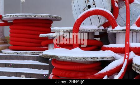 Grandi bobine di tubo corrugato flessibile rosso utilizzate per proteggere i cavi negli impianti elettrici. Un sacco di tubo flessibile in plastica di polietilene colorato utilizzato in contro Foto Stock