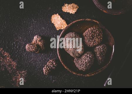 Tartufo nero in ciotola su sfondo scuro, delicatezza da cucina Foto Stock