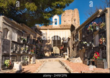 El Castell de Guadalest, Alicante, Spagna 02.17.22 Cimitero Muro tombe in un giardino commemorativo. Su pino sospeso. Fiori freschi. Ingresso con cancello, Cappella Foto Stock