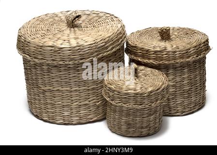 Primo piano del gruppo tre un piccolo cesto medio e grande tessuto di paglia o salice con coperchio decorativo su sfondo bianco Foto Stock