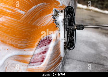 Dettagli sul pennello lasciando tratti nel sapone e schiuma di un giallo auto lavata. Foto Stock