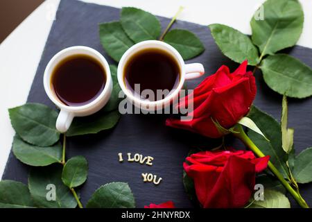 L'iscrizione ti amo su sfondo nero, caffè, rose rosse, primo piano Foto Stock