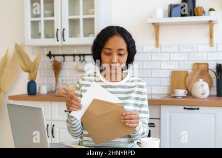 Donna afroamericana che invia la lettera. Preparazione della corrispondenza per la consegna della posta. Chiusura della busta Foto Stock