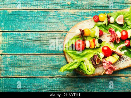 Antipasto di gamberetti, jamon, frutta e verdure su spiedini di legno.piatto Lay Foto Stock