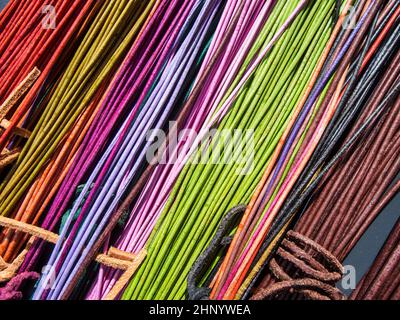 Cavi in pelle di colore rosso e arancione con nodi su un tavolo alla luce del sole in una vista obliqua. Foto Stock