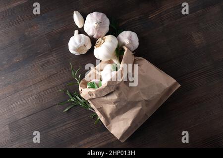 Sacchetto di carta con aglio, prezzemolo e rosmarino su sfondo di legno Foto Stock