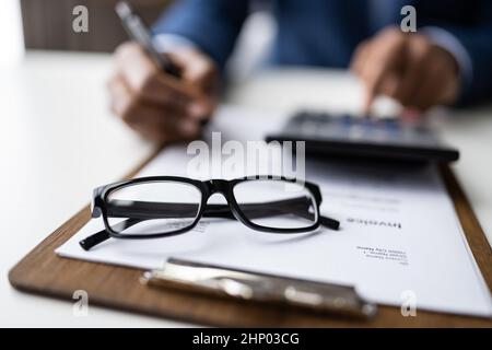 Businessman che calcola fattura usando calcolatore alla scrivania di legno Foto Stock