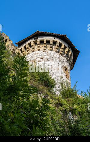 Massicce alte mura e una torre di un antico castello medievale Foto Stock