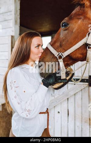 Verticale bella cavallo donna equestrienne baciare. Pulizia della pulizia della cura del corpo Foto Stock