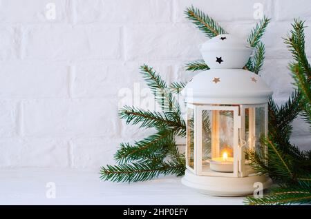 Decorazioni minimaliste natalizie in interni scandinavi Lanterna bianca e rami di abete. Spazio di copia Foto Stock