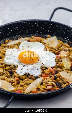 lenticchie con carne affumicata e cipolla servite con uova fritte Foto Stock