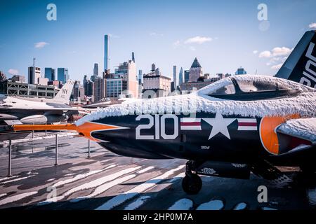 Vista di un aereo da caccia F-9 Cougar sul ponte di volo della USS Intrepid Sea, Air and Space Museum di fronte allo skyline di Manhattan, New York, NY, USA Foto Stock