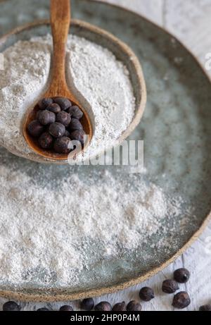 Piatto di farina di ceci nera e cucchiaio di legno di fagioli primo piano su tavola di legno bianco. Fagioli tradizionali della Puglia e della Basilicata in Italia Foto Stock