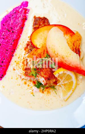 Orate di mare orata filetto burro pan fritto con pesche fresche di potare e fette dragonfruit timo sulla parte superiore Foto Stock