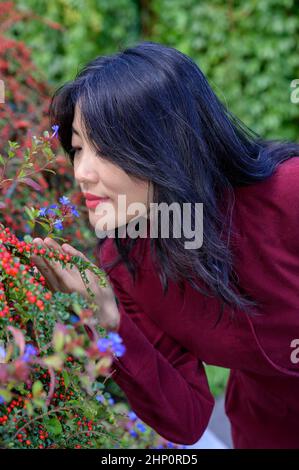 Bella donna cinese con lunghi capelli neri in una soleggiata giornata autunnale in città. Foto Stock