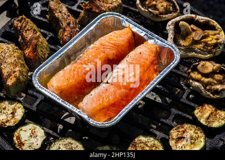 carne di vitello, salmone e zucchine su griglia da giardino con carbone Foto Stock