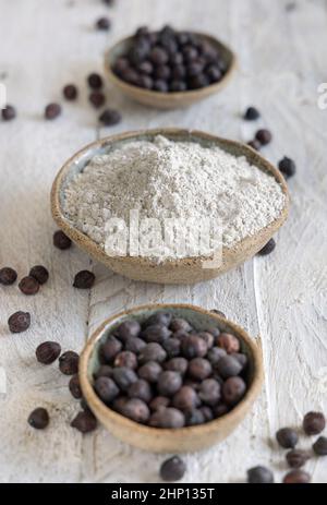 Ciotole di farina di ceci nera e cucchiaio di legno di fagioli da vicino su tavola bianca di legno. Fagioli tradizionali della Puglia e della Basilicata in Italia Foto Stock