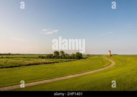 Il paesaggio verde del faro di Pilsum con turbine eoliche all'orizzonte, Pilsum, Krummhoern, Frisia orientale, bassa Sassonia, Germania Foto Stock