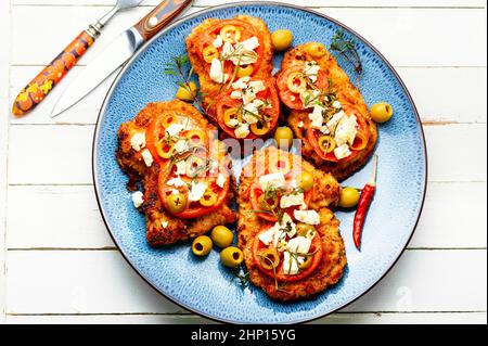 Sottile strato di carne, impanato in pangrattato con formaggio, olive e pomodoro. Piatto di carne - schnitzel Foto Stock