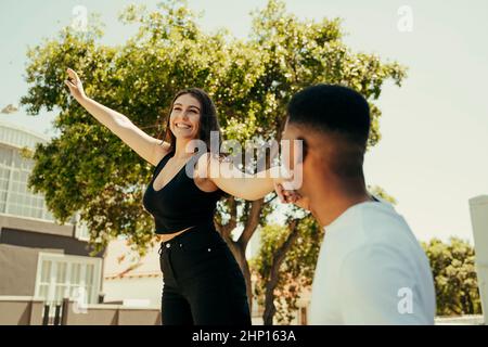 Coppia biraciale che tiene le mani a piedi nel parco Foto Stock