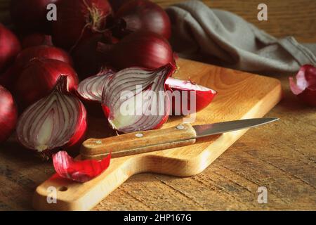 Cipolle rosse su tagliere di legno su sfondo di legno scuro a struttura rustica. Vista dall'alto, spazio per il testo . Foto Stock