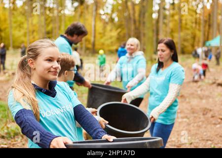 Bambini e volontari in una campagna di protezione ambientale nella foresta e raccolta di rifiuti Foto Stock