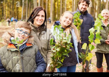 Famiglia e bambini come volontari con piantine di alberi per un rimboschimento sostenibile Foto Stock