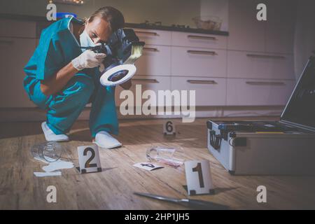 Specialista forense in tuta protettiva per scattare delle foto su una scena del crimine Foto Stock