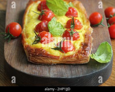 Crostata di pomodoro fresco, pasta sfoglia ricoperta di ricotta, formaggio e pomodori ciliegini . Foto Stock