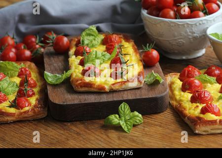 Crostata di pomodoro fresco, pasta sfoglia ricoperta di ricotta, formaggio e pomodori ciliegini . Foto Stock