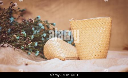 Set di cestino vuoto in vimini sul tavolo con sfondo in lino naturale e verde pianta, modello mock up per la visualizzazione del prodotto Foto Stock