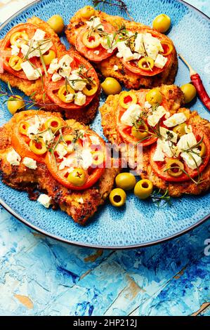 Sottile strato di carne, impanato in pangrattato con formaggio, olive e pomodoro. Piatto di carne - schnitzel Foto Stock