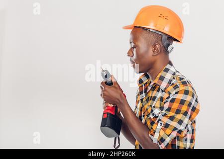 African American lavoratore edile nel casco utilizza cacciavite elettrico Foto Stock