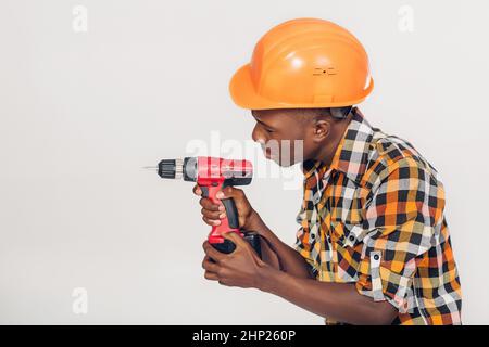 African American lavoratore edile nel casco utilizza cacciavite elettrico Foto Stock