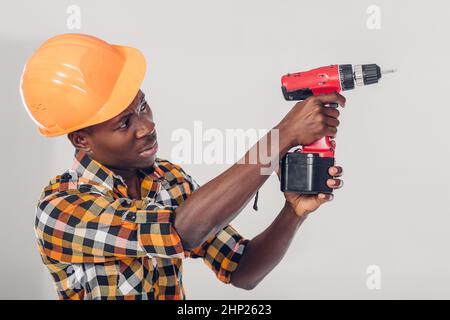 African American lavoratore edile nel casco utilizza cacciavite elettrico Foto Stock