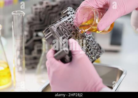 L'assistente di laboratorio versa l'olio sul cambio, in primo piano Foto Stock