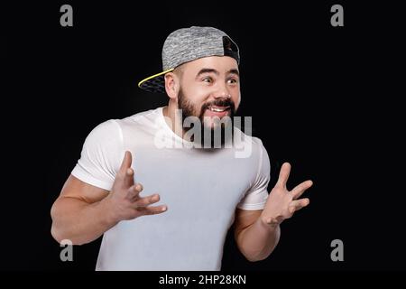 Triste barbuto appassionato di calcio nel cappuccio urlando su sfondo nero. l uomo guardare sport e team di supporto Foto Stock