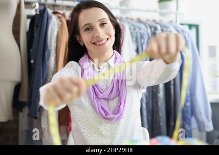 Il seamstress nell'atelier mostra un nastro di misurazione Foto Stock