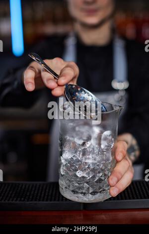 Il barista professionista crea un cocktail alcolico con ghiaccio utilizzando un filtro. Primo piano Foto Stock