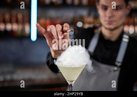 il barman sta sorseggiando un cocktail con una bolla d'aria fumosa al bar, primo piano Foto Stock