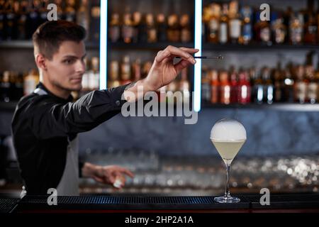 bel barman sta facendo un cocktail con bolle d'aria fumé al bar Foto Stock