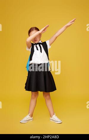 studentessa elegante con zaino blu isolato su sfondo giallo. bambino felice è pronto ad imparare. Foto Stock