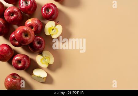 Un sacco di mele poste su sfondo beige, tagliate a metà o quarto. Composizione vista dall'alto. Foto Stock