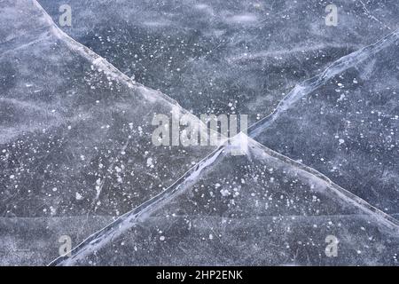 Crepe nel ghiaccio su una superficie di lago ghiacciata Foto Stock