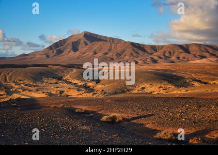 Costa de Papagayo a Lanzarote, Spagna. La catena montuosa Los Ajaches al tramonto. Una serata di sole con alcune nuvole in un cielo blu, ora d'oro. Foto Stock