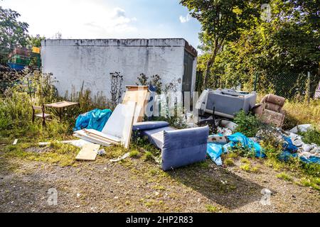 Rifiuti ingombranti illegali sul lato della strada con mobili vecchi Foto Stock