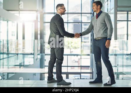 Lavorare insieme per il successo. Colpo di due uomini d'affari che scuotono le mani insieme in un ufficio. Foto Stock